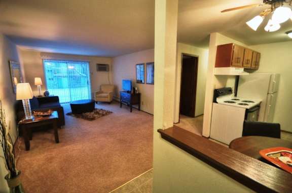 an open living room and a kitchen with a stove and refrigerator