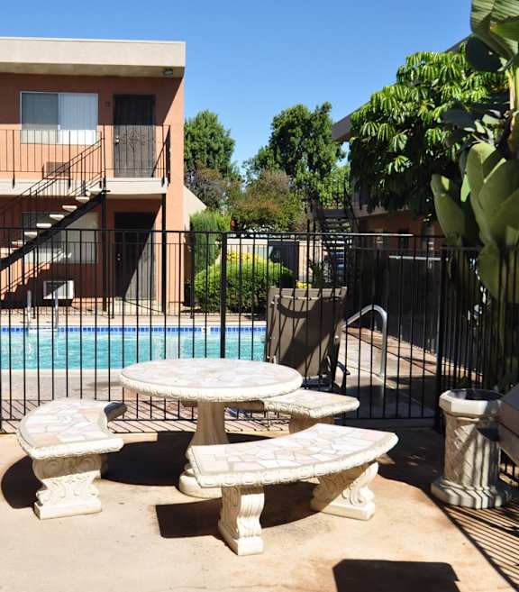 A poolside area with a table and chairs and a television.