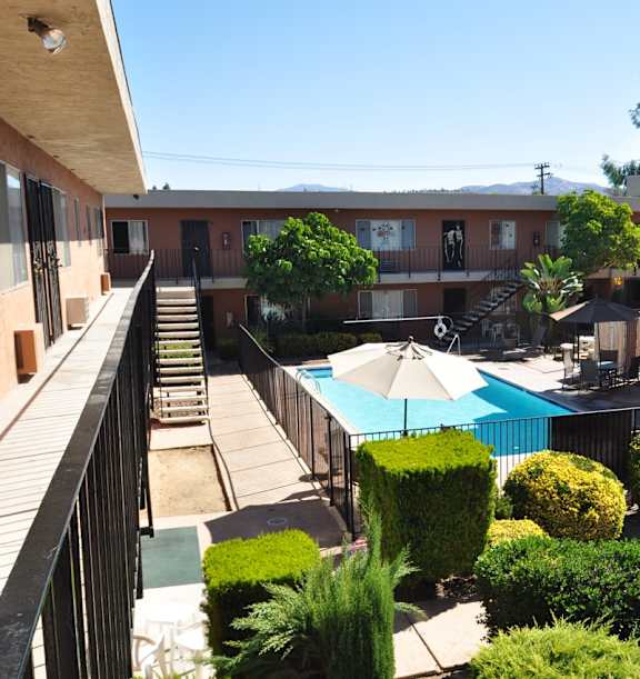 A pool surrounded by bushes and trees in a courtyard.
