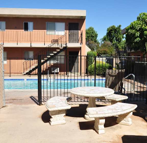 A poolside area with a table and chairs and a television.