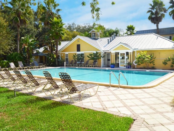 a large pool in front of a house with palm trees
