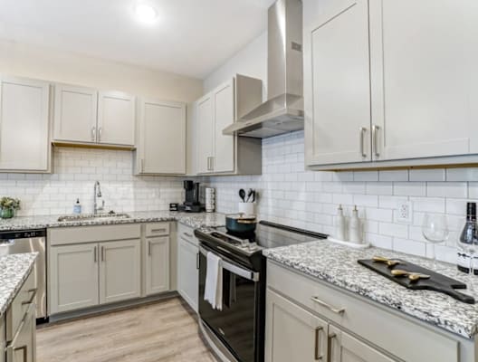 A kitchen with a black stove top oven and white cabinets.