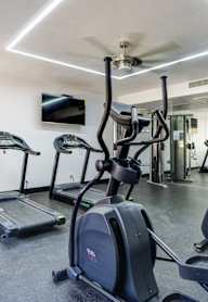a gym with exercise equipment and a ceiling fan