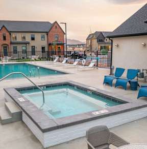 A hot tub sits in the middle of a patio with chairs around it.