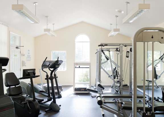 a gym with cardio machines and windows