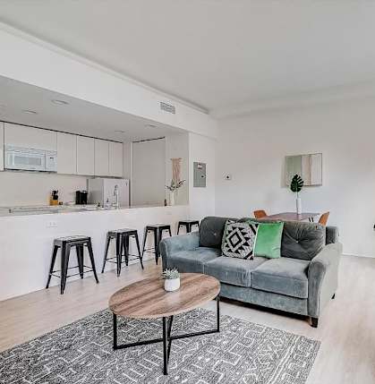 a living room with a couch and a kitchen with a bar at Lofts at 629, Ohio, 44114