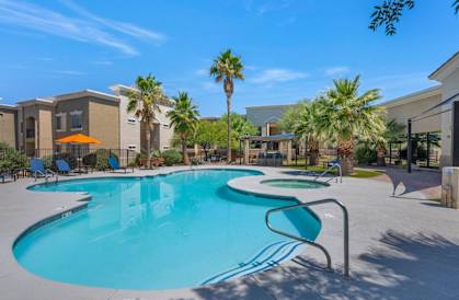 A swimming pool surrounded by palm trees and lounge chairs.