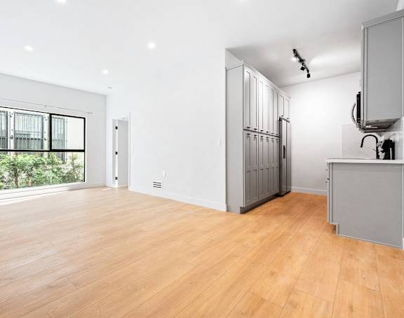 A spacious room with wooden floors and white walls.