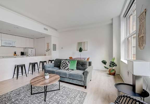 a living room with a couch and a kitchen with a bar at Lofts at 629, Ohio, 44114