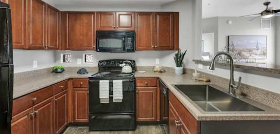 A kitchen with wooden cabinets and black appliances.