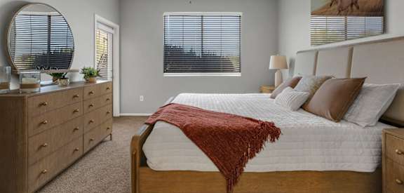 A bedroom with a bed, dresser, and ceiling fan.