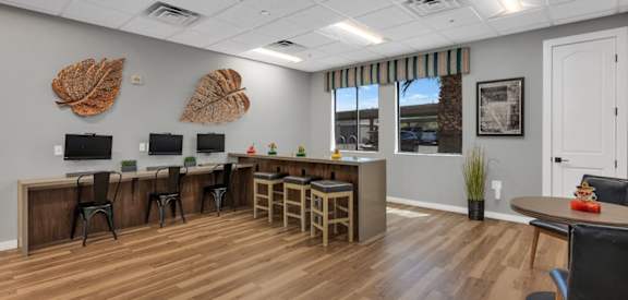A room with wooden floors and a white ceiling with a row of desks and chairs.