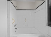 Thumbnail 10 of 20 - a white tiled bathroom with a tub and a window