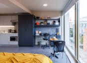 Thumbnail 4 of 8 - a bedroom with a bed and two chairs in front of a window