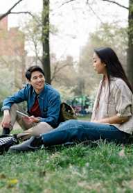 Three people sitting on the grass in a park.