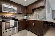 A kitchen with a stainless steel oven and wooden cabinets.