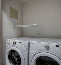 Two white front loading washing machines in a small laundry room.