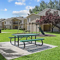 a picnic area with a swing set in front of an apartment complex