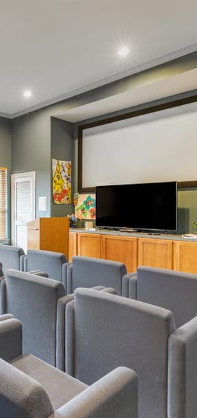 a room with movie theater style chairs and a flat screen tv