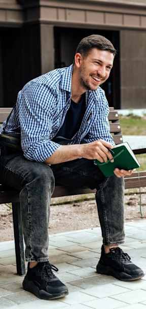 A man is sitting on a bench reading a book.