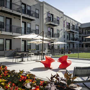 an outdoor patio with chairs and umbrellas in front of an apartment building