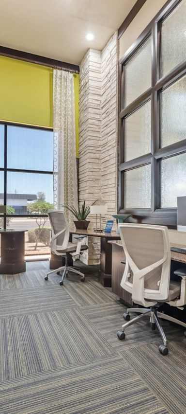 A room with a carpeted floor and a wooden desk with a computer on it.