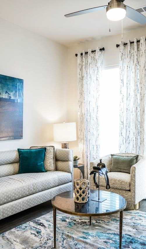 A living room with a couch, a painting, a chair, a table, and a rug.