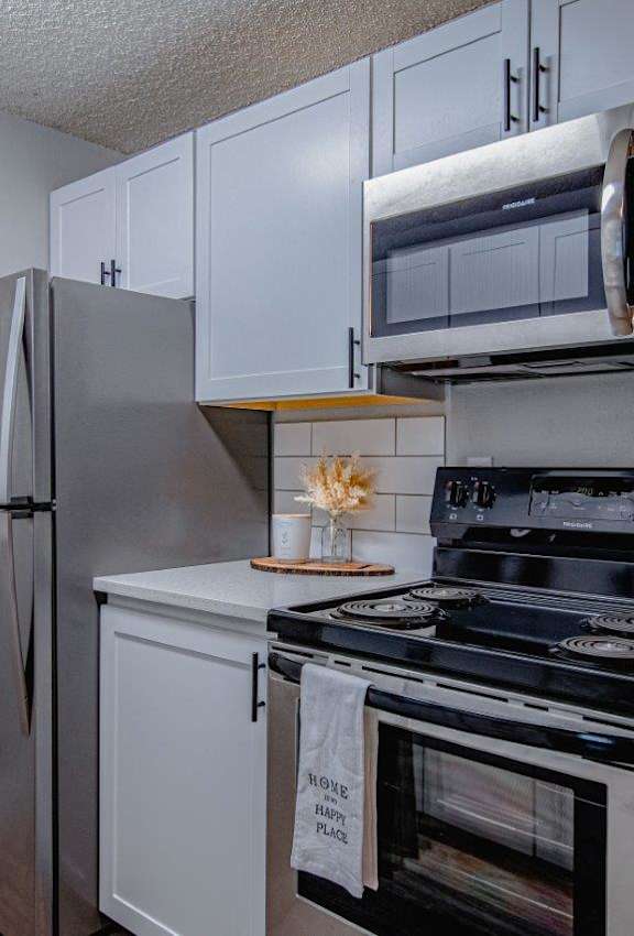 A kitchen with a stainless steel refrigerator, microwave, and oven.