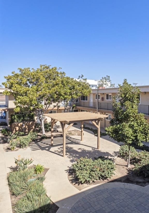 a courtyard with a picnic table and trees in the middle of an apartment building