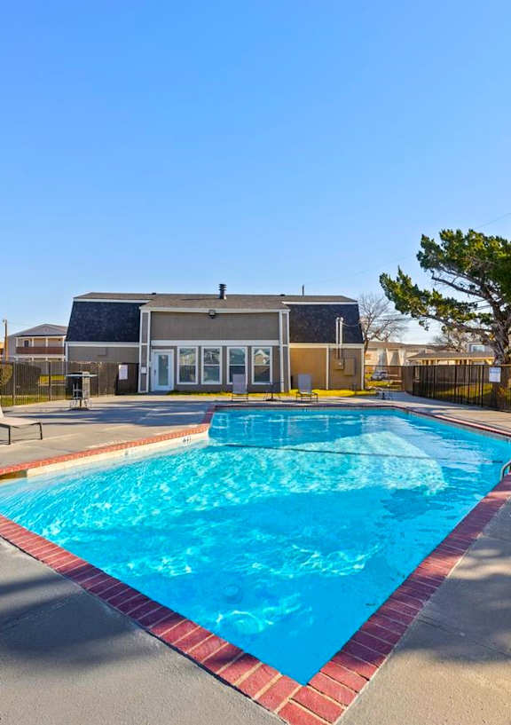A swimming pool surrounded by a fence and chairs.