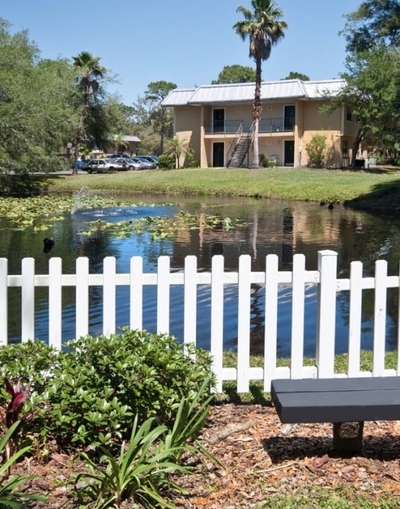 a white fence and a pond in front of a house