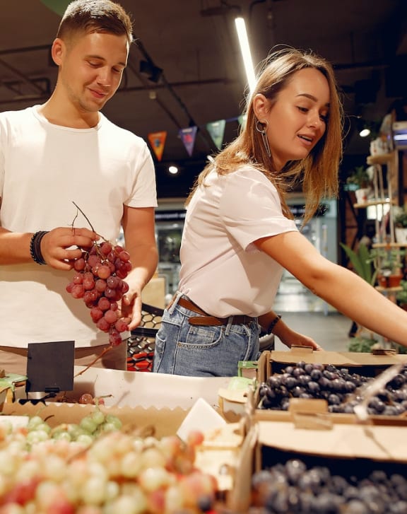 a couple buys grapes at a market