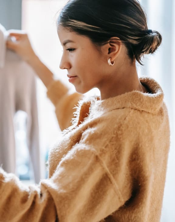a woman looking at a shirt on a hanger