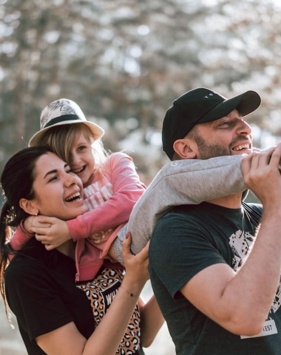 a man and woman holding a little girl in their arms