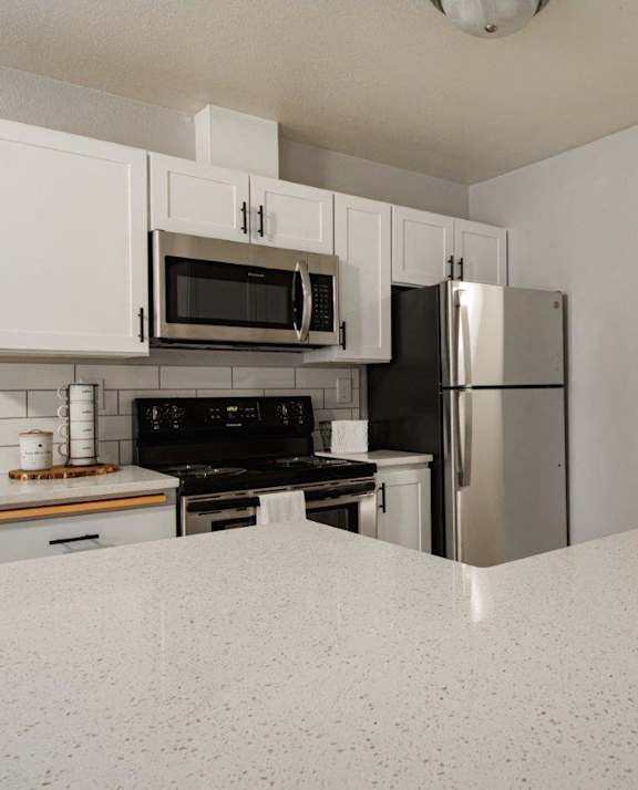 A kitchen with white cabinets and a black stove top oven.