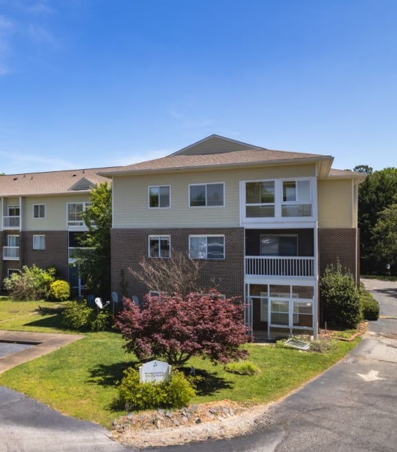 an apartment building with a lawn and trees in front of it