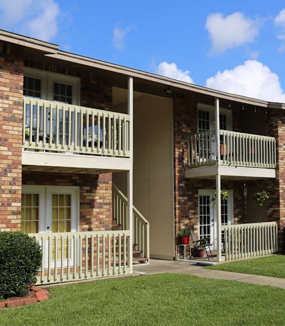 A brick building with a balcony and a white fence.