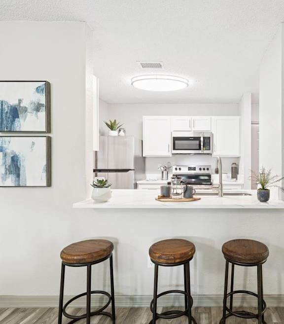 Model kitchen with bar stools at Mirage on Kernan Apartment in Jacksonville, FL