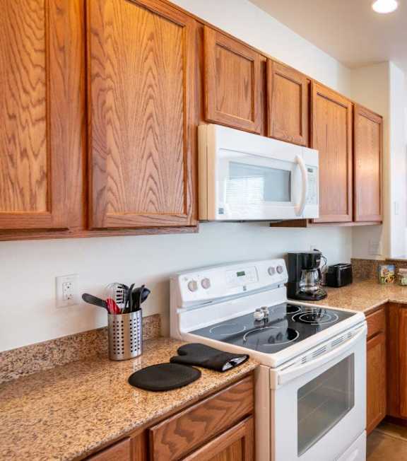 A kitchen with wooden cabinets and a white stove top oven.