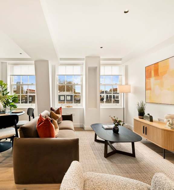 A living room with a brown couch, a black coffee table, and a large painting on the wall.