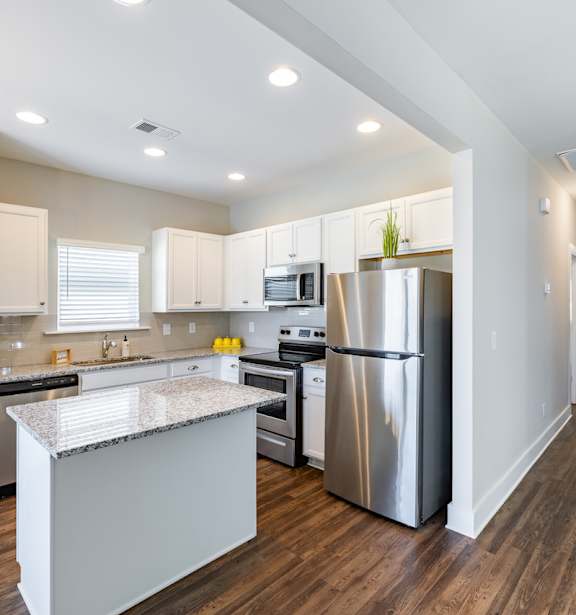 A large kitchen with granite countertops, stainless steel appliances, and tall ceilings