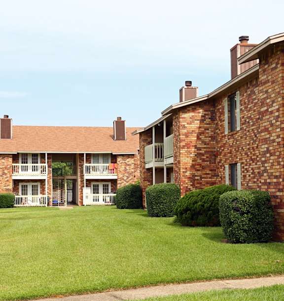 A brick building with a green lawn in front.