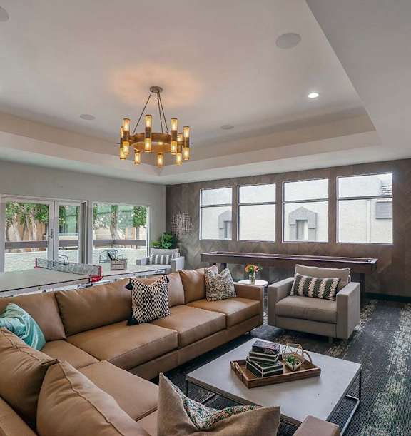 A living room with a brown couch and a chandelier.