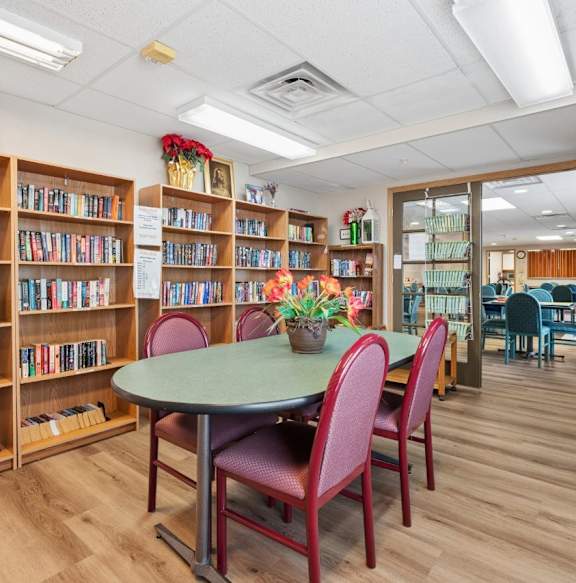 A library with a table and chairs in the middle of the room.