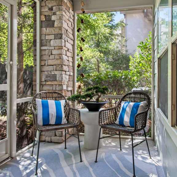 Two chairs with blue and white stripes sit on a porch.