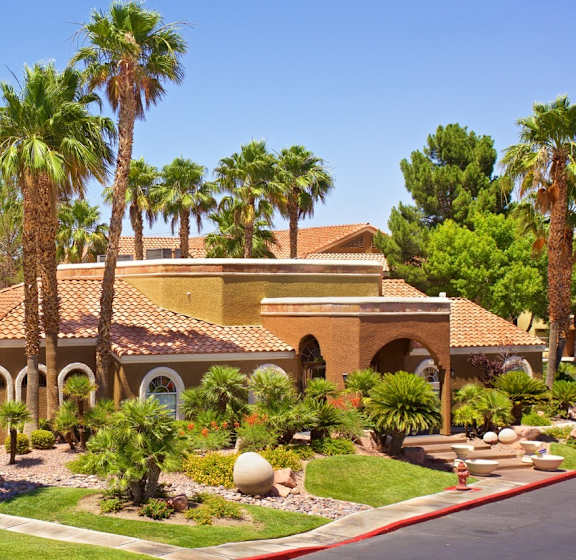 A house with a red roof and palm trees in front.