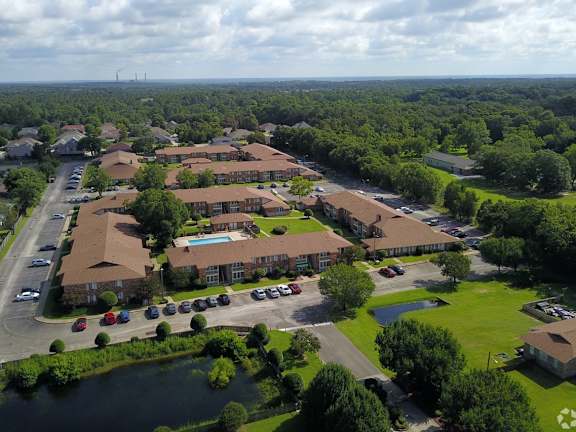 A bird's eye view of a residential complex with a pond in the foreground.