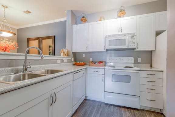 a kitchen with white appliances and white cabinets and a sink