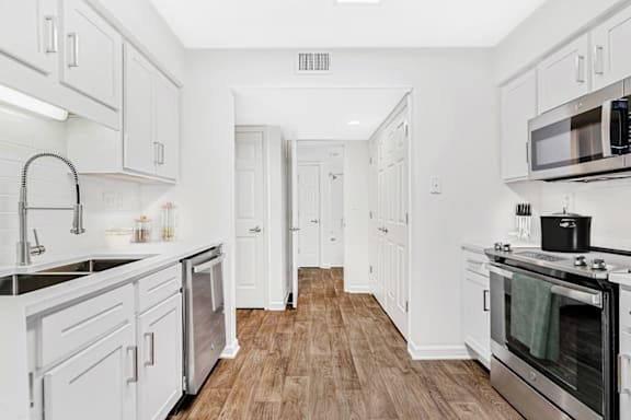 a kitchen with white cabinetry and a wooden floor at Caveness Farms Apartments, Wake Forest, NC