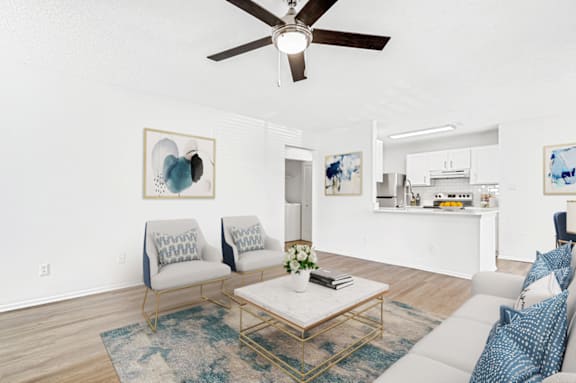 A living room with a white couch, a coffee table, and a ceiling fan. at Bridges at Mallard Creek Apartment Homes, Charlotte, 28269